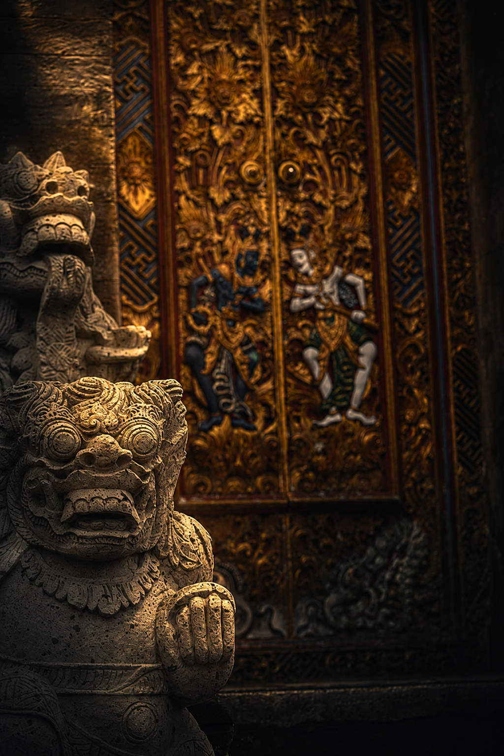 Stone guardian beside a gilded temple door